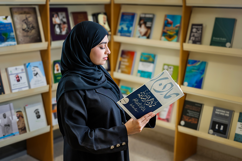 طالبة تقرأ كتاب في المكتبة