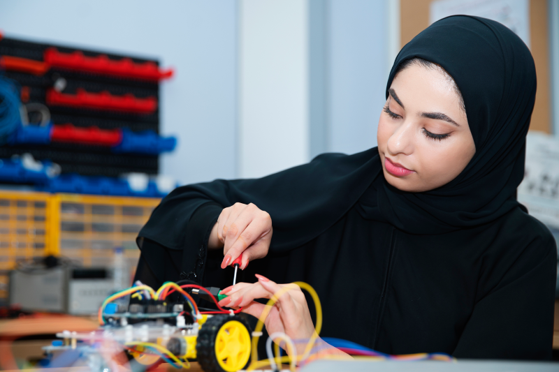 Researcher assembling electronic components on a small robotic vehicle at the Center for Artificial Intelligence and Digital Innovation, United Arab Emirates University.