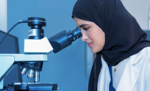 باحث يفحص عينات نباتية داخل بيتٍ زجاجي في مركز خليفة للهندسة الوراثية والتقنية الحيوية بجامعة الإمارات العربية المتحدة.