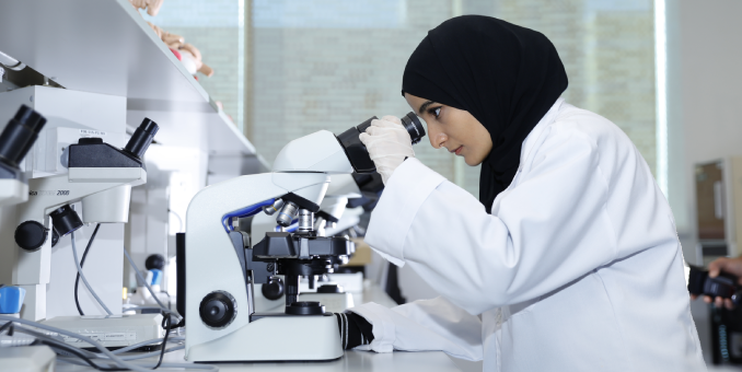 باحثة في مختبر المركز الوطني للمياه والطاقة في جامعة الإمارات العربية المتحدة تقوم بإجراء تحليل باستخدام المجهر.