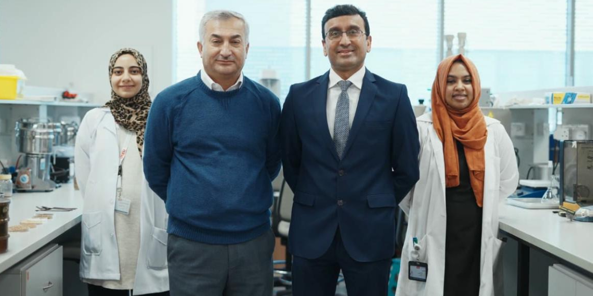أعضاء فريق بحثي من جامعة الإمارات العربية المتحدة يرتدون المعاطف المخبرية ويقفون معًا في أحد المختبرات.